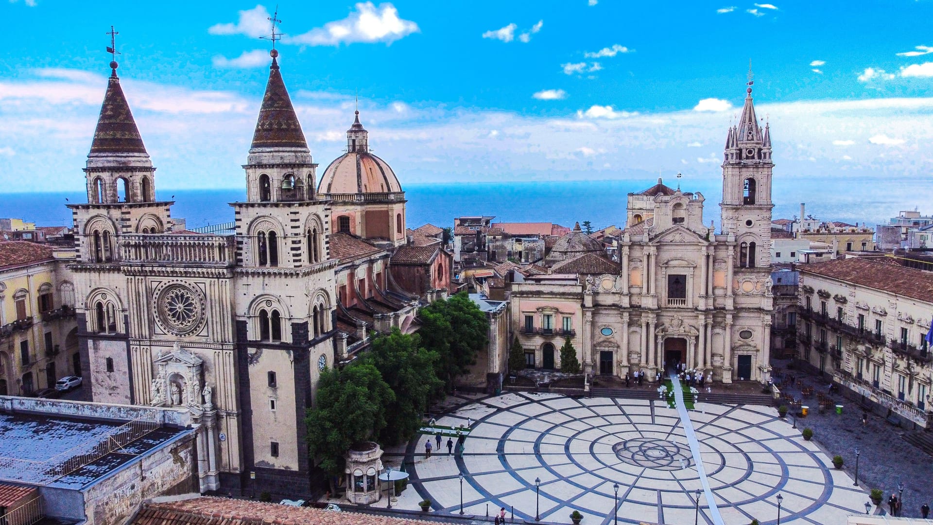 Veduta aerea di piazza Duomo ad Acireale con la Cattedrale, la basilica dei Santi Pietro e Paolo e il mare sullo sfondo